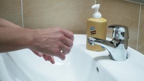 Video of close-up of mature woman washing her hands with liquid soap under the water tap in the bathroom. Hygiene concept hand detail.