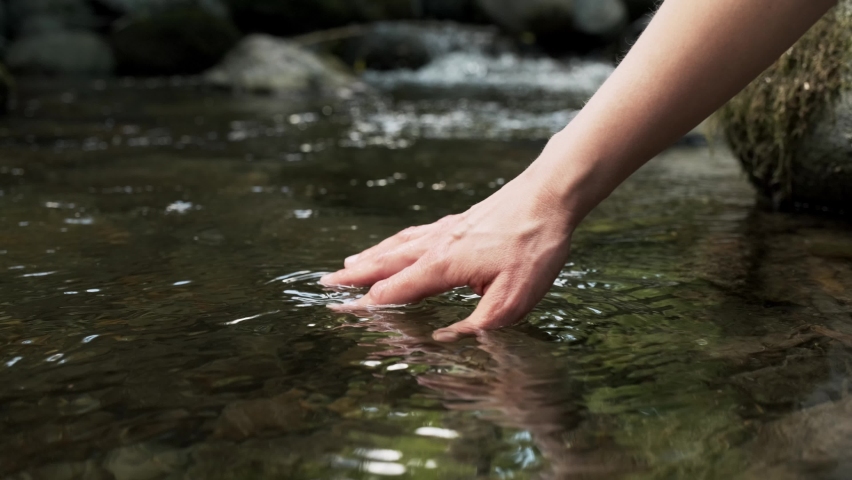 Video of close-up of woman hands touching and wetting the water of a lake in the mountain. | Shutterstock HD Video #1058699728