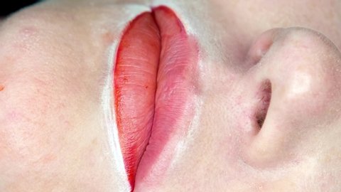 Cosmetologist making lips microblading permanent procedure using tattoo machine and pink pigment.