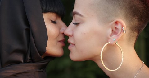 Young lesbian muslim woman in hijab kissing her girlfriend.