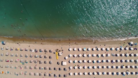 Aerial top view of sea, beach, sand, umbrellas and happy people. Summer seascape.