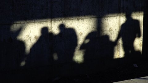 Shadows of the people on a concrete wall in slow motion