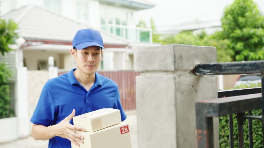 Young Asia postal delivery courier man in blue shirt handling parcel boxes for sending to customer at house and Asian female receive delivered package outdoors. Package shopping food delivery concept. | Shutterstock HD Video #1058713282