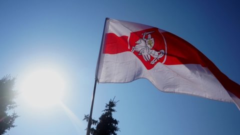 White-red-white flag flies in wind against background of sky. Symbol of Belarusian protest against dictatorship. Support of public situation in Belarus. Historical flag of Belarus.