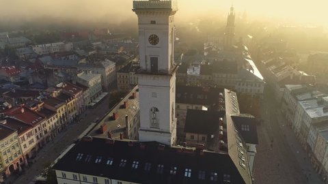 Flying over morning foggy Lviv city in Ukraine. Scenic summer aerial view of the Market Square architecture in the Old Town of Lviv, Ukraine. Town hall and Market Square bird's-eye. Summer misty