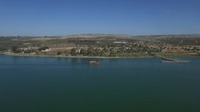 Wide aerial of boat approaching Capernaum shore. Sea of Galilee. 