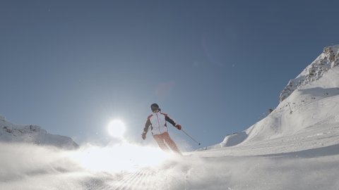 one Man downhill skier slowly down the ideal ski slope. Skiing on the track against the backdrop of picturesque snow-capped mountains. Winter outdoor activities. Slow motion, 2K RAW footage, 2704x1520