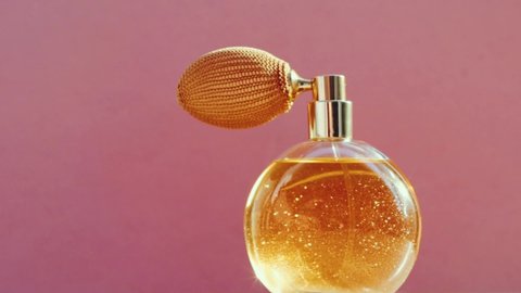 Luxury golden perfume bottle and shining light flares on pink background, glamorous fragrance scent as perfumery product for cosmetic and beauty brand, stock footage