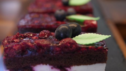 Line of red velvet berry jellied cakes decorated with blueberries and leave in patisserie
