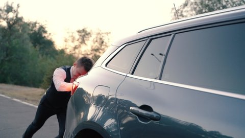 Front view of a businessman pushing a car with empty fuel tank. Vehicle with trouble.