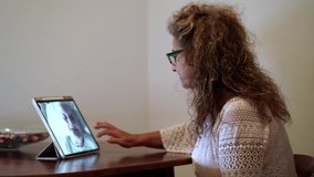 Side shot of a spanish woman making a video call on a tablet with her mother infected with coronavirus COVID 19 while staying at the hospital thanks to the volunteer team that make that calls