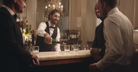Male bartender serving drinks to group of men at party. Barman serving alcohol to guest at a nightclub. 
