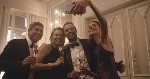 Woman taking selfie with friends at gala night. Two couple enjoying a party and taking selfie with mobile phone.
