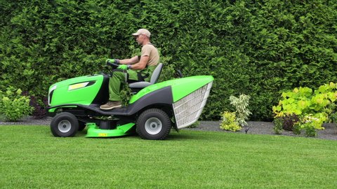 Upkeep Of Large Private Backyard Lawn And Garden. Man On Tractor Lawn Mower Cutting And Maintaining Healthy Grass .