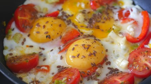 Fried Eggs Prepared On a Frying Pan with red vegetables, tomatoes, paprika and celery sprinkled with dill