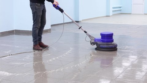 the cleaner washes a pier with a professional polisher machine. Cleaning floor in office building lobby