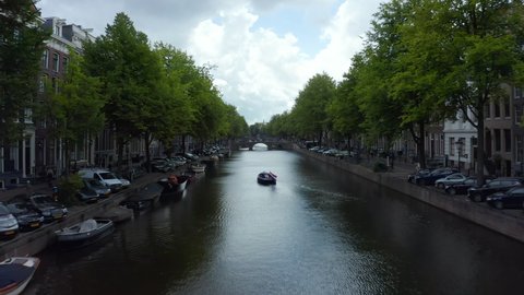 Amsterdam Canal with Boat and Dutch Flag waving in wind, forward Aerial 