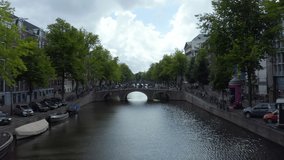Establisher over Amsterdam Canal with Boat and Dutch Flag waving in wind, backwards Aerial - Powered by Shutterstock - Get 15% off with code: PIKWIZARD15