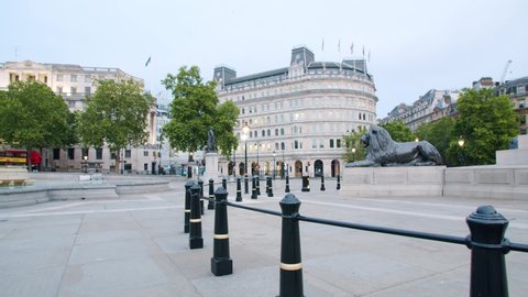 Lockdown in London, Slow motion Gilmbal pan of Empty Trafalgar Square during coronavirus pandemic 2020, with one lone car & walker in empty streets with flying birds.