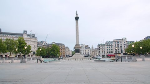 Lockdown in London, Slow motion Gilmbal walk of Nelson's Column in Empty Trafalgar Square during coronavirus pandemic 2020, red London bus in empty streets with flying birds.