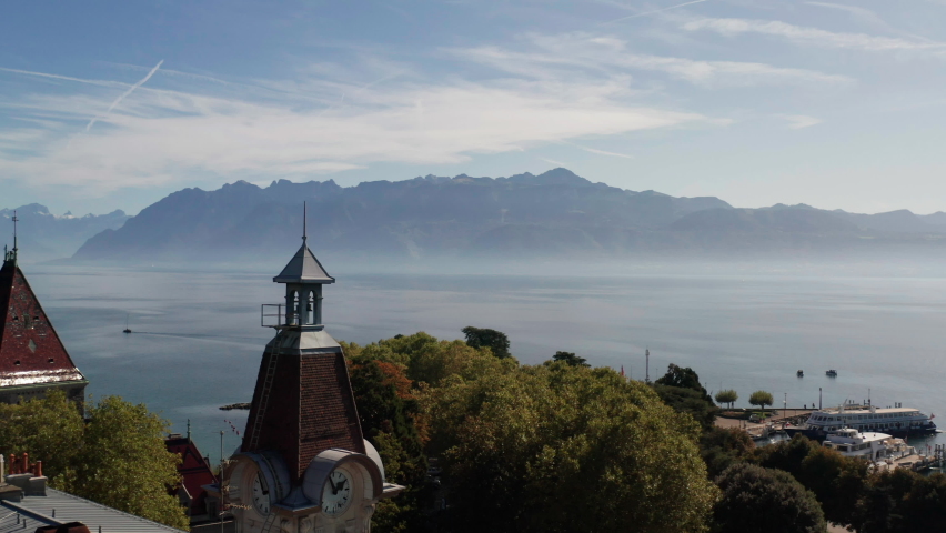 Aerial of clock tower overlooking a large and beautiful lake with mountains in the distance
