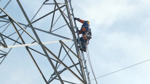 Electrician climbs up pylon, secured with a rope.