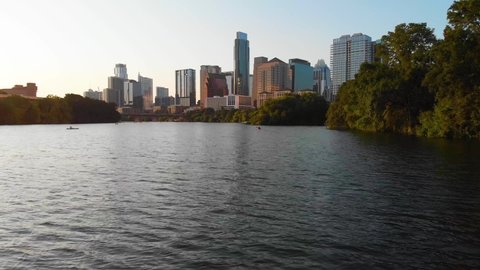 Low drone shot of a Kayaker paddling towards Downtown Austin Texas. Shot August 2020