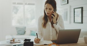 Attractive young professional woman talks on phone while working from home, productive lifestyle