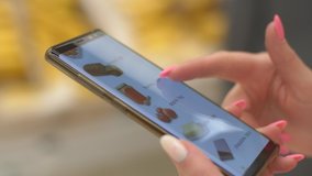 Close-up Side View Female Purchaser Looking Shopping List in Smart Phone Inside Grocery Store. Person Reading Check List on Display in Healthy Lifestyle App Indoors Marketplace. Scrolling Mobile Phone. - Powered by Shutterstock - Get 15% off with code: PIKWIZARD15