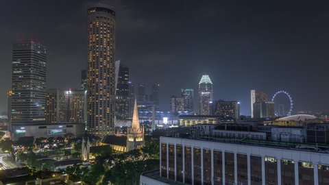 Singapore skyline with St. Andrew's Cathedral aerial night timelapse hyperlapse. It is an Anglican cathedral in Singapore, the country's largest cathedral. Skyscrapers on a background