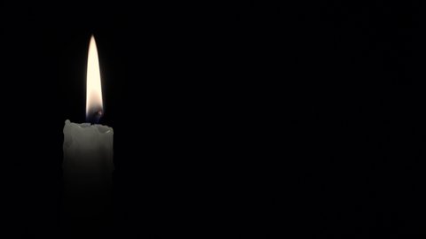 Candle. Seamlessly loop footage with copy space. Burning candle isolated on a black background. Infinitely flame of a white candle in the night.