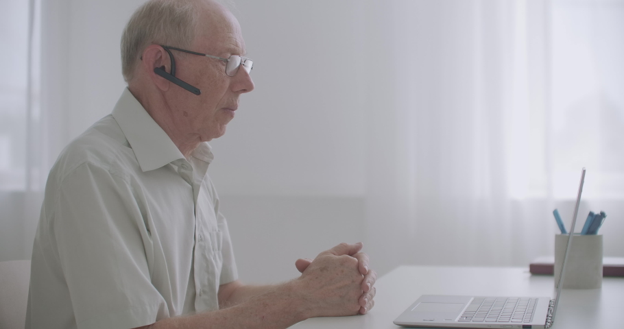 aged man is communicating with friends or colleagues by video call, talking looking at screen of laptop, online communication Royalty-Free Stock Footage #1058763958