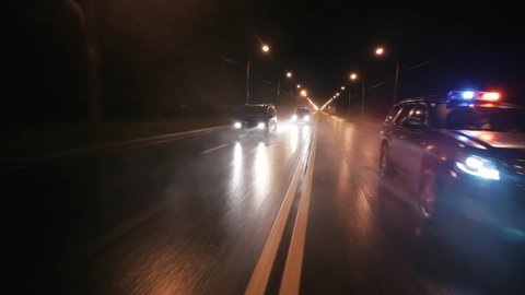 Police cars drive at high speed on the highway at night. It's raining hard. Outdoor front view of police traffic auto driving. Car active driving. Flashers.