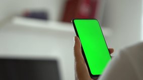 Handheld Camera: Point of View of Woman at Modern Room Sitting on a Chair Using Phone With Green Mock-up Screen Chroma Key Surfing Internet Watching Content Videos Blogs Tapping on Center Screen