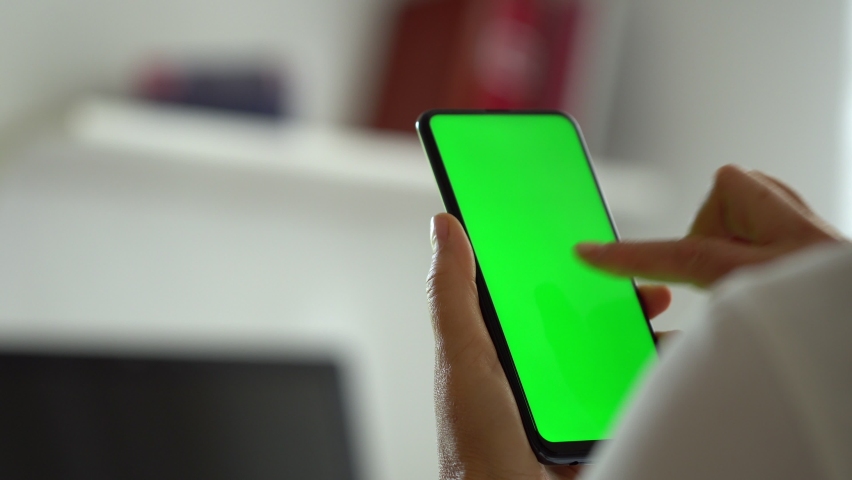 Handheld Camera: Point of View of Woman at Modern Room Sitting on a Chair Using Phone With Green Mock-up Screen Chroma Key Surfing Internet Watching Content Videos Blogs Tapping on Center Screen | Shutterstock HD Video #1058768311