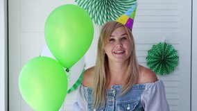 A woman with a cap on her head waves her hand, looking at the camera. Online birthday. St. Patrick's Day Celebration - Powered by Shutterstock - Get 15% off with code: PIKWIZARD15