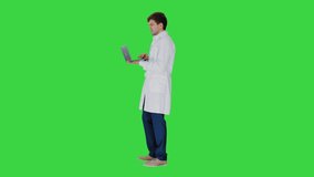 Male doctor in white coat having video conference on his laptop on a Green Screen, Chroma Key.