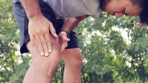 Asian man injured their knees from exercise. Knee pain massage
