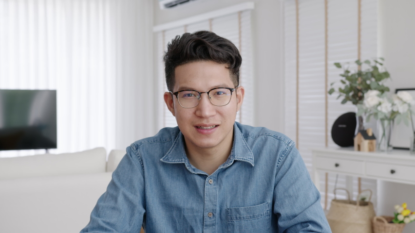 Medium shot ,confident asian creative man vlogger make live video conference call, chat online on computer and sitting on table at home, Webcam view, video chat and Self isolation concept. | Shutterstock HD Video #1058778940