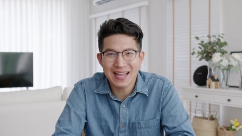 Medium shot ,confident asian creative man vlogger make live video conference call, chat online on computer and sitting on table at home, Webcam view, video chat and Self isolation concept.