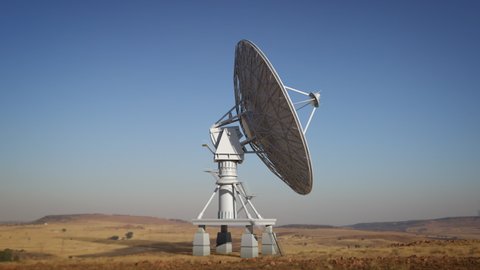 Large ground satellite isolated on desert environment, big satellite dish rotating in loop searching the sky during day.