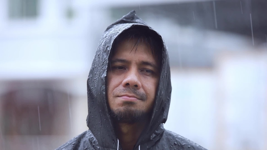Portrait Asian man wearing a raincoat in the rain slow motion Royalty-Free Stock Footage #1058781001