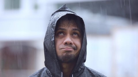 Portrait Asian man wearing a raincoat in the rain slow motion