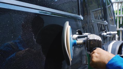 Close up of car mechanic using an orbital polisher while polishing a black car for shiny. Shot in 4k resolution