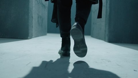 Close up of male legs in black boots.  Rear back view of man walking inside dark maze. Man walking inside dark room, corridor. Footage of mystical video. Shot on ARRI ALEXA Cinema Camera in slow motio