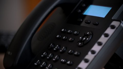 Office worker uses a landline phone to answer incoming calls and dialing a number to make a call
