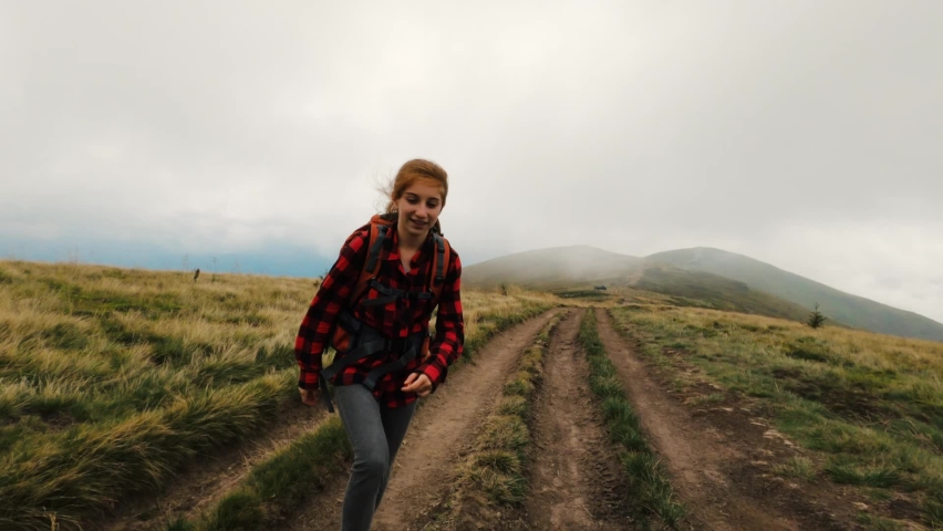 Young girl tourist on the trail in mountains on a trekking path