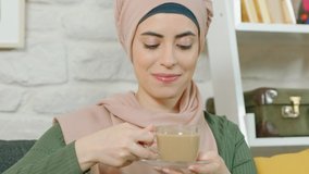 Close up and slow motion video.Beautiful Muslim woman drinking hot milk with milk. The Muslim woman smells and drinks pleasantly before drinking hot milk flavored coffee or tea.
