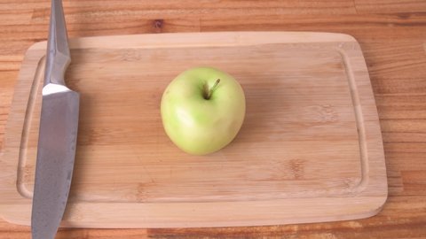 Cutting green apple in slices on wood board side view