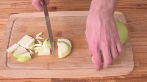 Cutting green apple in slices on wood board side view